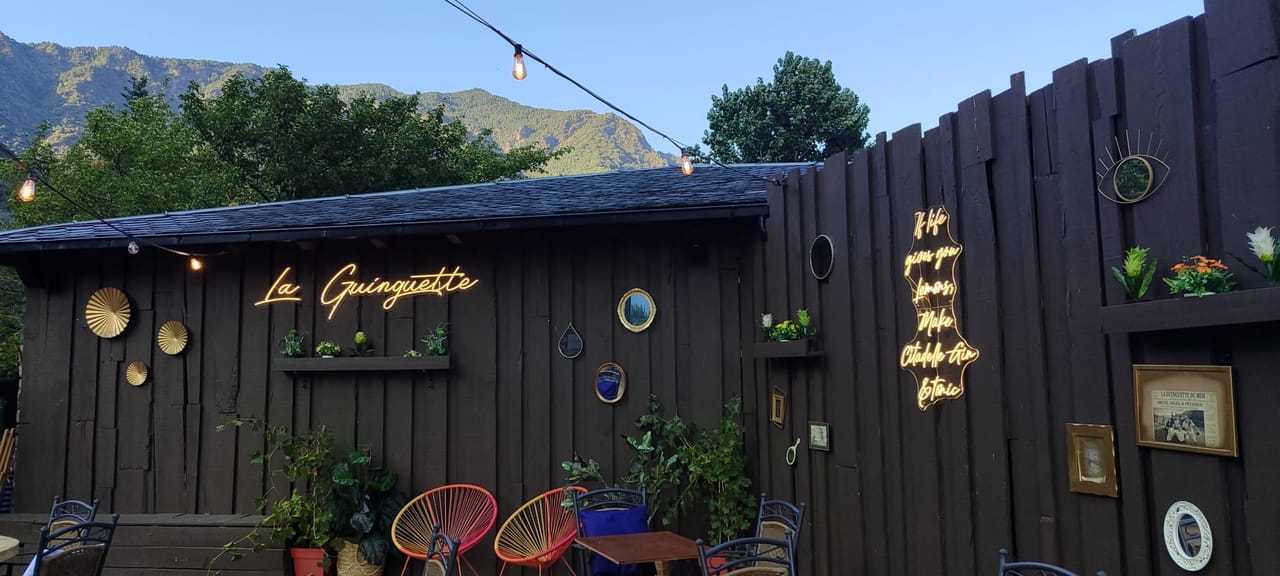 Chaises colorées et décor doré devant la cabane en bois de La Guinguette