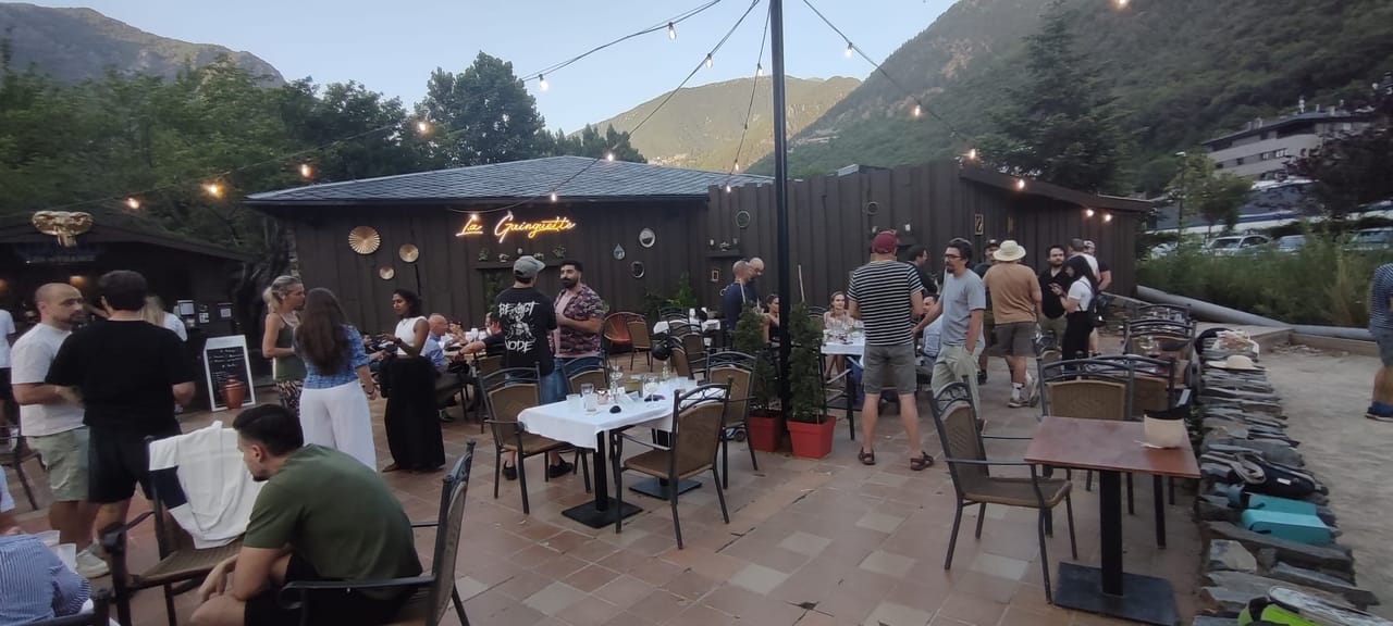 La terrasse de La Guinguette animée à la tombée du soir, sous les guirlandes, face aux montagnes d'Andorre